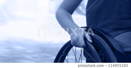 Boy's hand on the wheel of a wheelchair Boy's hand on the wheel of a wheelchair 114955193