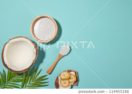 Design template with tropical fruit ingredient including coconut and banana, it placed on blue table top with blank space on the right side for showing product of fruit extract, top view shot 114955288