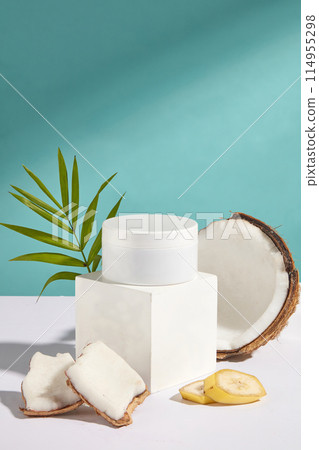 A blank label cosmetic jar in white displayed on a rectangular showcase platform over blue background, coconut and banana placed around. Photo for promotion has frontal shot and designing space A blank label cosmetic jar in white displayed on a rectangular showcase platform over blue background, coconut and banana placed around. Photo for promotion has frontal shot and designing space 114955298