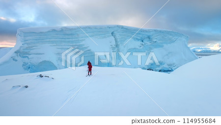 Two men ski on Antarctica snow hill glacier in sunset. Travel, active lifestyle, sport, recreation in Arctic wild nature landscape. Snow covered mountains, icy ocean, winter scene. Aerial drone flight Two men ski on Antarctica snow hill glacier in sunset. Travel, active lifestyle, sport, recreation in Arctic wild nature landscape. Snow covered mountains, icy ocean, winter scene. Aerial drone flight 114955684