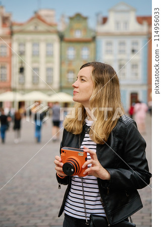 Female traveler taking picture with vintage instant camera 114956033