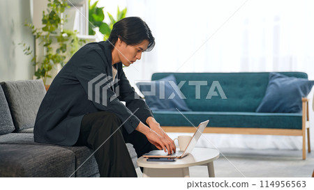一個男人在客廳裡使用筆記本電腦 114956563