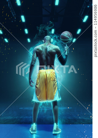 Rear view of muscular man, basketball player spinning ball on finger, showing strength and determination. Neon background with smoke effect 114956986