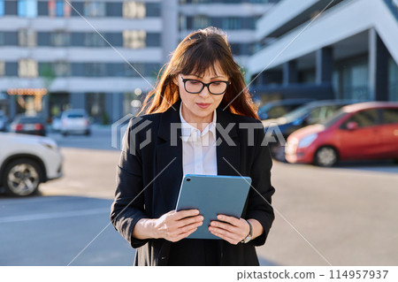 Mature woman manager agent using digital tablet for work, city background Mature woman manager agent using digital tablet for work, city background 114957937