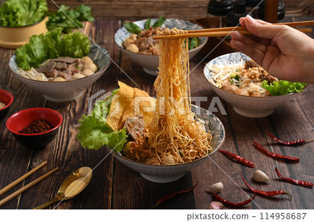 Hand using chopsticks to picking up tasty spicy egg noodles from bowl. Thai noodles and Asian food concept Hand using chopsticks to picking up tasty spicy egg noodles from bowl. Thai noodles and Asian food concept 114958687