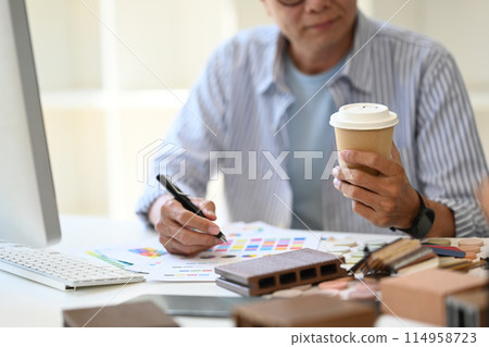 Cropped shot of senior architect with paper cup of coffee sitting in the creative office 114958723