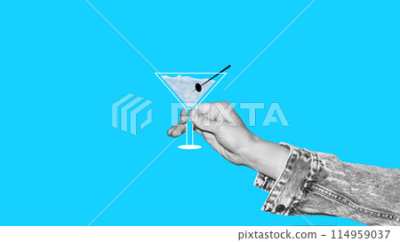 Person holding Martini cocktail with olive decoration against blue background. Creative colorful design. Monochrome and color Person holding Martini cocktail with olive decoration against blue background. Creative colorful design. Monochrome and color 114959037