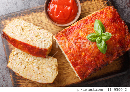 Meatloaf with chicken mince, onion and garlic glazed with ketchup closeup on the wooden board. Horizontal top view 114959042