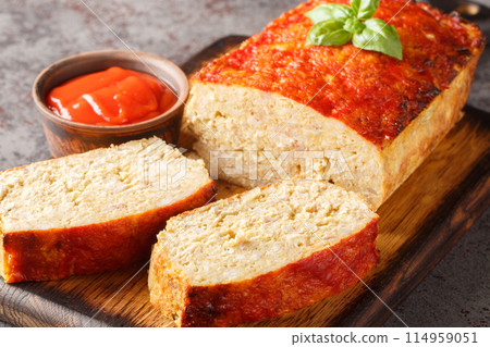 Meatloaf with chicken mince, onion and garlic glazed with ketchup closeup on the wooden board. Horizontal 114959051