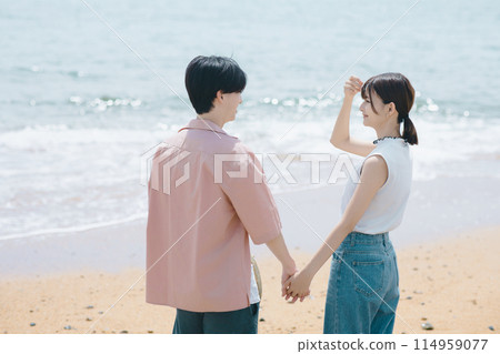 A young couple walking along the beach A young couple walking along the beach 114959077