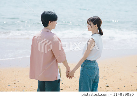 A young couple walking along the beach 114959080