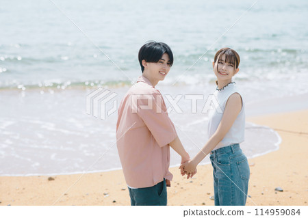A young couple walking along the beach A young couple walking along the beach 114959084