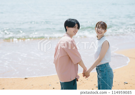 A young couple walking along the beach A young couple walking along the beach 114959085