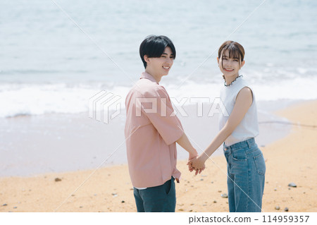 A young couple walking along the beach A young couple walking along the beach 114959357