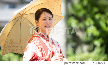 A woman in a yukata with a parasol looking at the camera A woman in a yukata with a parasol looking at the camera 114960221