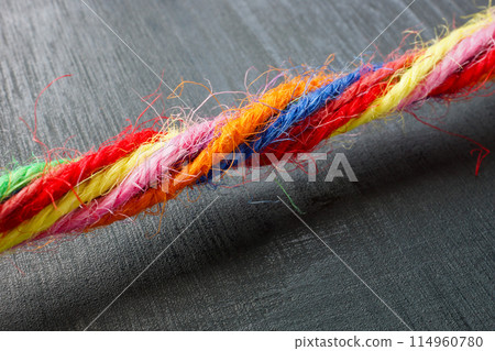 Close-up of a rope made of colored threads as a symbol of unity and inclusion. Close-up of a rope made of colored threads as a symbol of unity and inclusion. 114960780