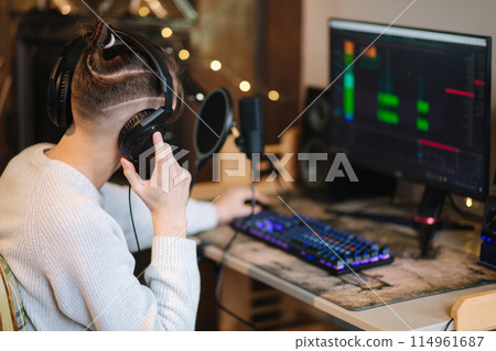 Young happy dj man wearing headphones and working at home. Making music or melody in special app Young happy dj man wearing headphones and working at home. Making music or melody in special app 114961687