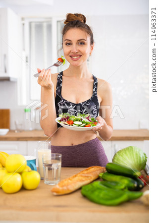 Sportive woman eating vegetable salad at home 114963371