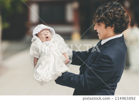 Father and son rejoice as they hold their son in their arms at a shrine visit 114963892