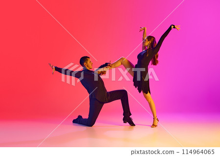 Man and woman, ballroom dancers, performing full of feelings tango dance in neon lighting against vibrant gradient background. 114964065