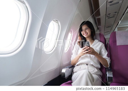 Asian businesswoman using smartphone on airplane during flight Asian businesswoman using smartphone on airplane during flight 114965183