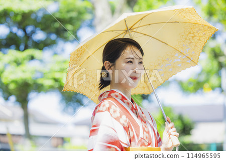 A woman walking outdoors in a yukata with a parasol A woman walking outdoors in a yukata with a parasol 114965595
