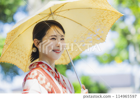 A woman walking outdoors in a yukata with a parasol A woman walking outdoors in a yukata with a parasol 114965597