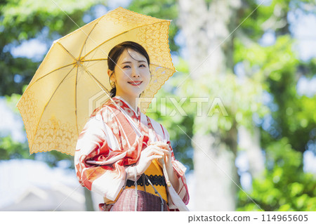 A woman walking outdoors in a yukata with a parasol 114965605