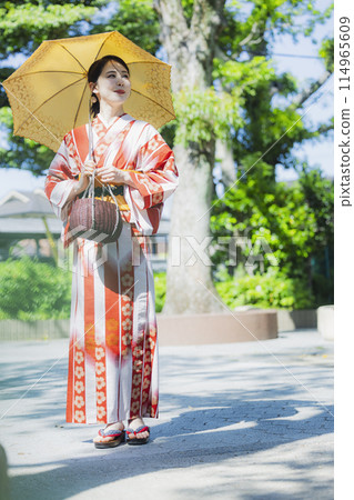 A woman walking outdoors in a yukata with a parasol 114965609