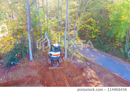 Construction is taking place as tractor uproots trees, clearing land for construction Construction is taking place as tractor uproots trees, clearing land for construction 114968436