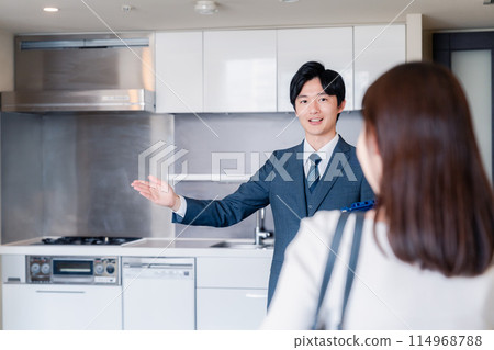 A man from a real estate agency showing around an apartment building 114968788