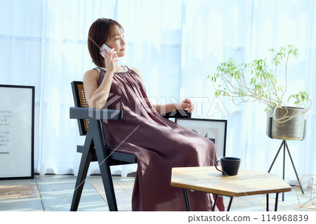 一個女人坐在房間的椅子上打電話 一個女人坐在房間的椅子上打電話 114968839