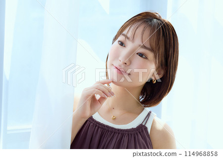 A woman relaxing in a room through lace curtains A woman relaxing in a room through lace curtains 114968858