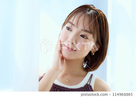 A woman relaxing in a room through lace curtains 114968865