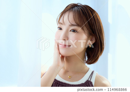 A woman relaxing in a room through lace curtains 114968866