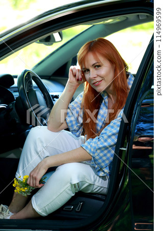 A girl poses for the camera with her car in nature. Joy, happiness, serenity. A girl with a car in nature. 114969599
