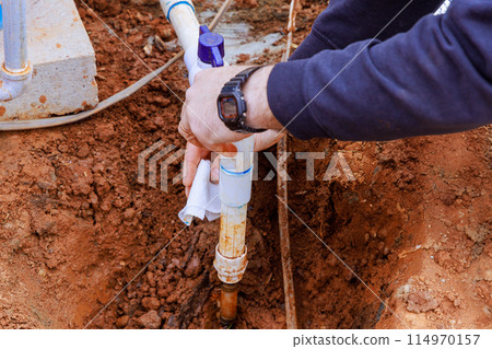 Plumber glues pipes to connect water to house Plumber glues pipes to connect water to house 114970157