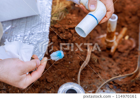 During course of repair work, technician plumber uses clear primer for PVC pipe with before gluing it together During course of repair work, technician plumber uses clear primer for PVC pipe with before gluing it together 114970161