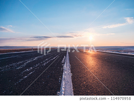 Empty rural road at sunset in winter with clearing skies 114970958