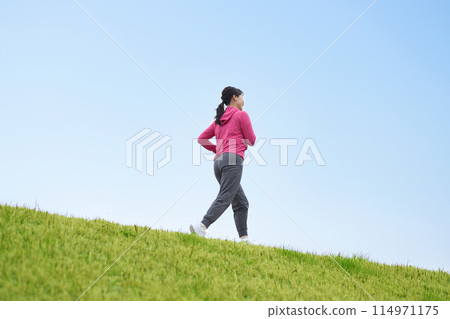 Middle-aged woman running in sportswear 114971175