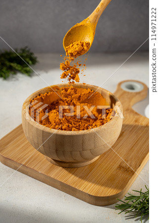 Curcuma Turmeric spice powder ground in a wooden bowl. Curcuma Turmeric spice powder ground in a wooden bowl. 114971222