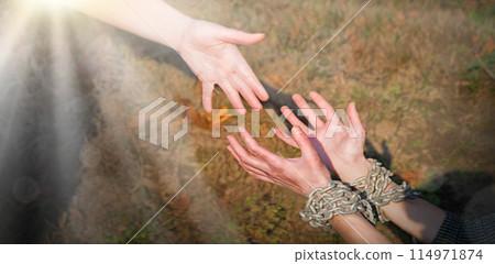 Bound hands reach out to the outstretched hand for help 114971874