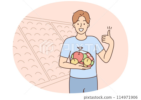 Smiling man with bag of apples in supermarket 114971906