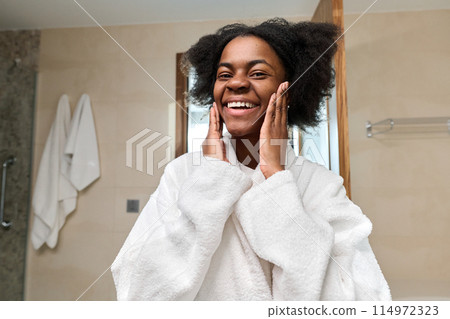 Portrait of young Black woman smiling at camera enjoying skincare in morning, copy space 114972323