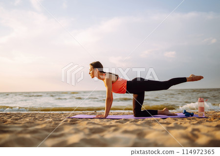 Young woman in sportswear doing yoga, fitness exerciseon the beach. Sport, Active life. Young woman in sportswear doing yoga, fitness exerciseon the beach. Sport, Active life. 114972365