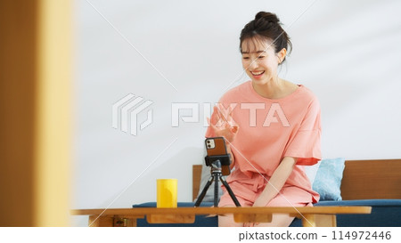 一位在智慧型手機上播放影片的女性主播 114972446