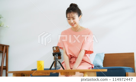 一位在智慧型手機上播放影片的女性主播 114972447