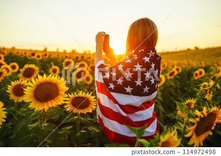 Beautiful girl with the American flag in a sunflower field. 4th of July. Fourth of July. Freedom. Beautiful girl with the American flag in a sunflower field. 4th of July. Fourth of July. Freedom. 114972498