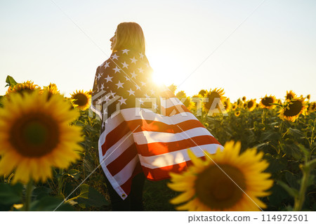 Beautiful girl with the American flag in a sunflower field. 4th of July. Fourth of July. Freedom. Beautiful girl with the American flag in a sunflower field. 4th of July. Fourth of July. Freedom. 114972501