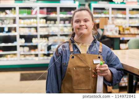 Waist up portrait of smiling young woman with Down syndrome working in supermarket and holding cleaning spray bottle copy space 114972841